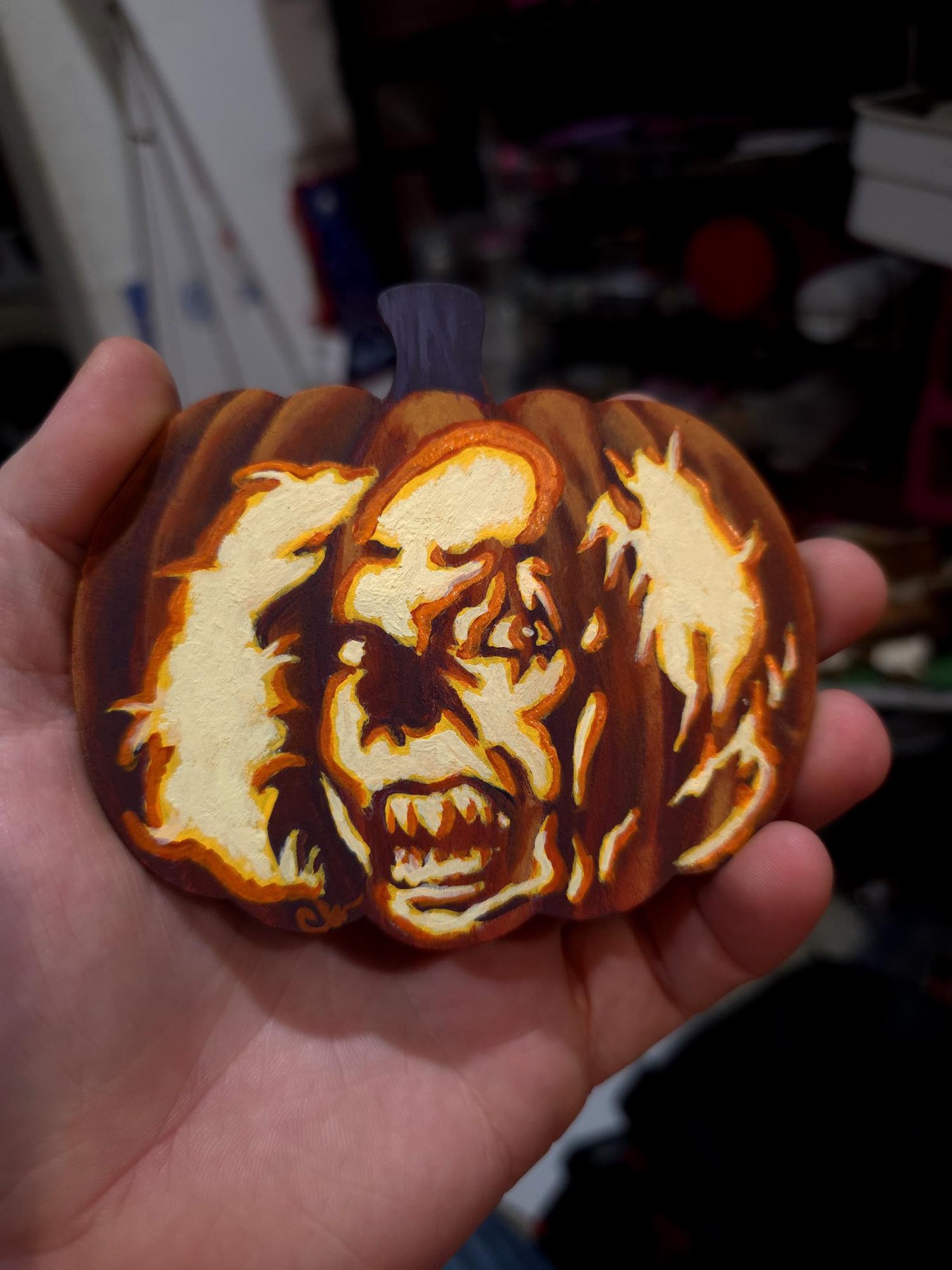 Small carved pumpkin with glowing creature face and wing-like shapes